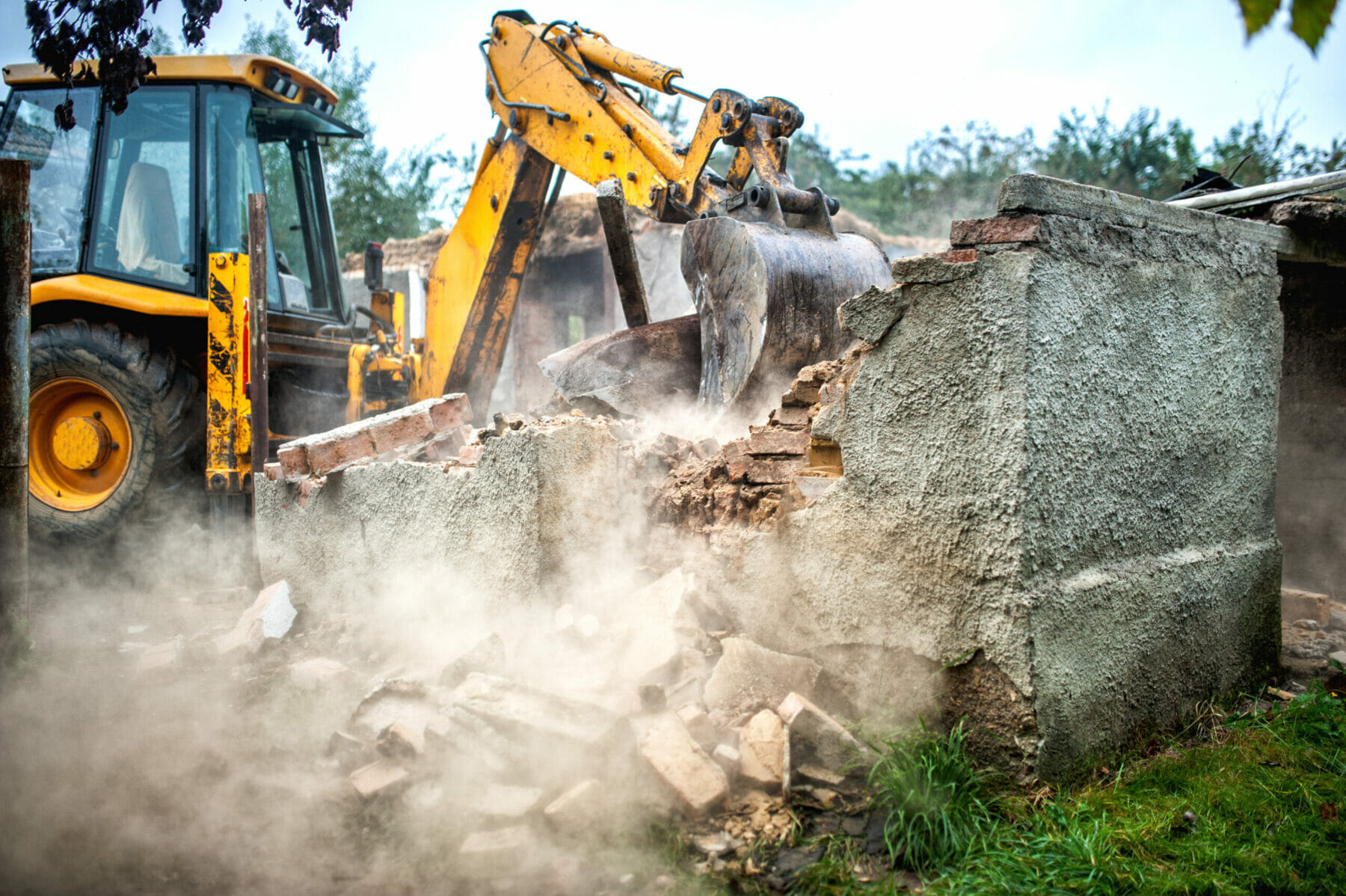 bulldozer demolishing concrete brick walls of small building